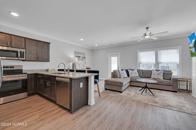 kitchen with light stone countertops, stainless steel appliances, light hardwood / wood-style floors, kitchen peninsula, and ceiling fan