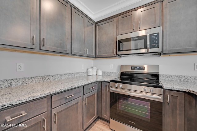 kitchen featuring light stone counters, ornamental molding, dark brown cabinetry, and appliances with stainless steel finishes