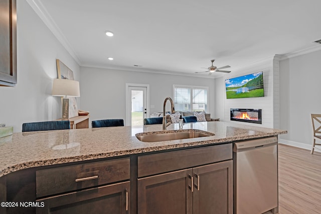 kitchen with dark brown cabinets, stainless steel dishwasher, a large fireplace, sink, and ceiling fan