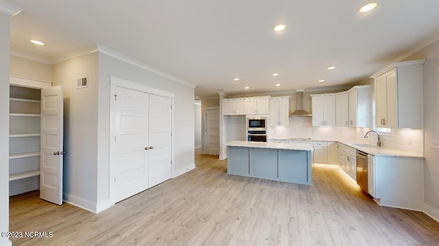 2090 Greenside Manor Dr Unit L-39, Ocean Isle Beach, NC 28469 - kitchen featuring crown molding, appliances with stainless steel finishes, tasteful backsplash, light wood-style flooring, and white cabinetry