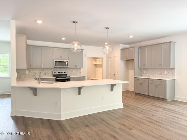 235 Weathersbee Dr, Hampstead, NC 28443 - kitchen with decorative backsplash, light wood-style floors, gray cabinets, a sink, and appliances with stainless steel finishes