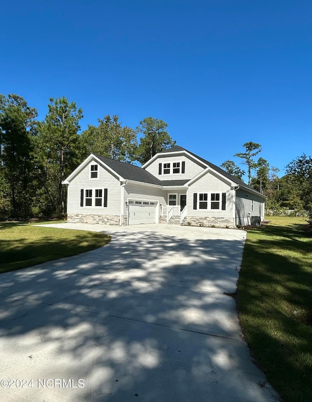 235 Weathersbee Dr, Hampstead, NC 28443 - bungalow featuring a garage, a front lawn, stone siding, and concrete driveway