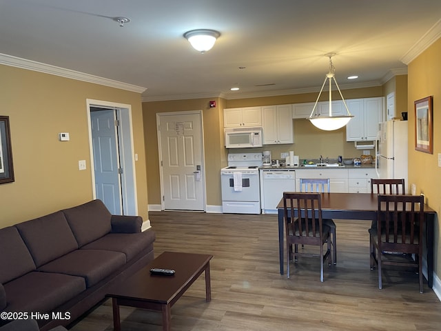 kitchen with decorative light fixtures, sink, crown molding, white appliances, and white cabinets