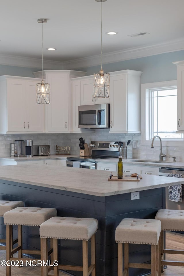 kitchen featuring backsplash, white cabinetry, hanging light fixtures, and stainless steel appliances