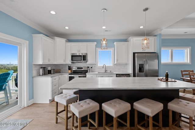 kitchen featuring white cabinets, appliances with stainless steel finishes, decorative light fixtures, and backsplash