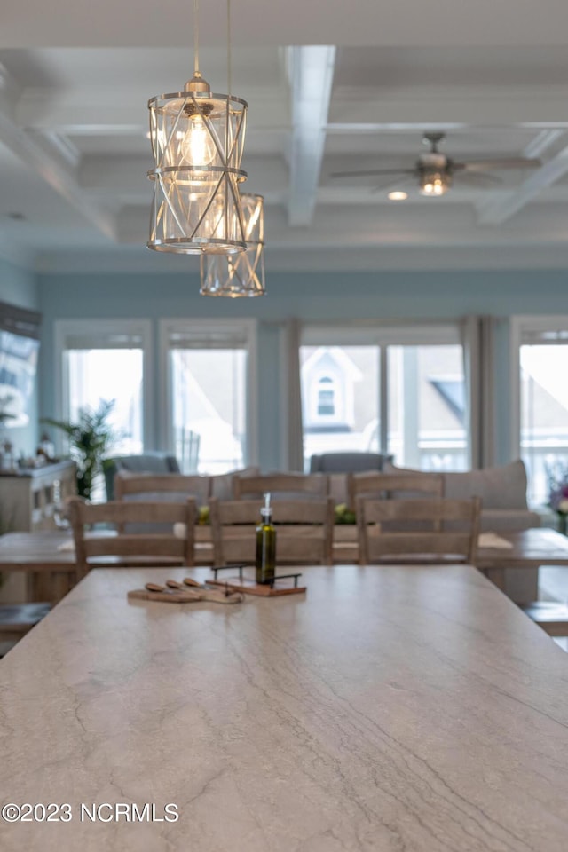 interior space featuring coffered ceiling, ceiling fan with notable chandelier, a wealth of natural light, and beamed ceiling