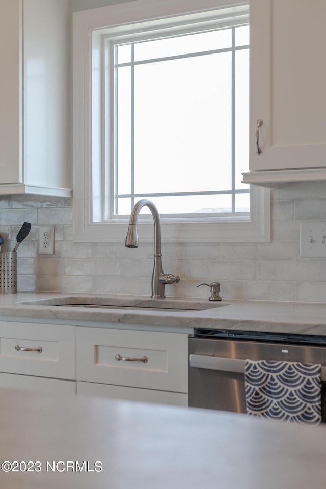 kitchen with white cabinets, dishwashing machine, tasteful backsplash, and sink