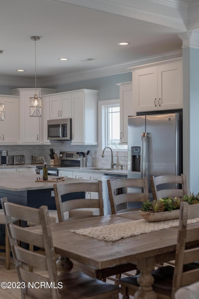 kitchen with decorative light fixtures, appliances with stainless steel finishes, light stone counters, white cabinets, and a notable chandelier