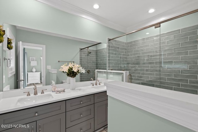 bathroom with a shower with door, vanity with extensive cabinet space, ornamental molding, and double sink