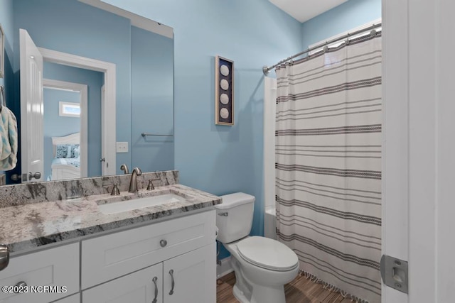 bathroom with toilet, vanity with extensive cabinet space, and hardwood / wood-style floors