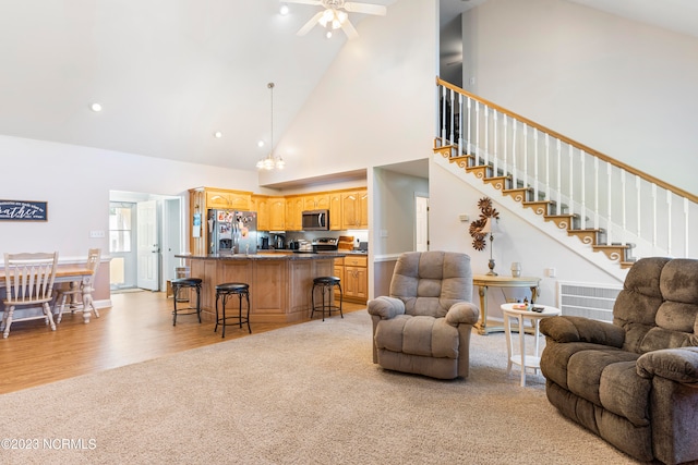 living room with light hardwood / wood-style floors, high vaulted ceiling, and ceiling fan