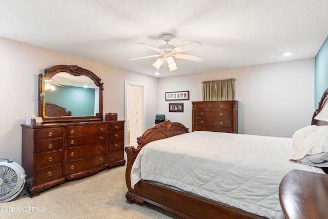 bedroom with a textured ceiling, ceiling fan, and light carpet