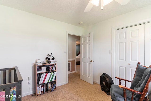 interior space featuring a textured ceiling, ceiling fan, and light carpet