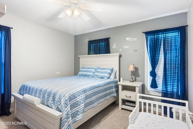 carpeted bedroom featuring ceiling fan and a textured ceiling