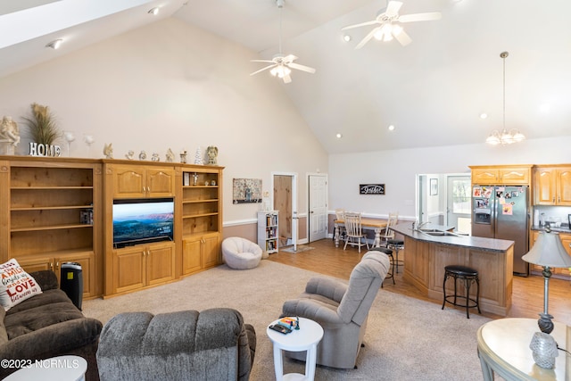 carpeted living room featuring ceiling fan with notable chandelier, sink, and high vaulted ceiling