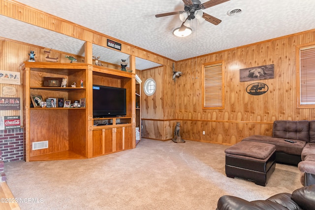 carpeted living room with ceiling fan, wooden walls, and a textured ceiling