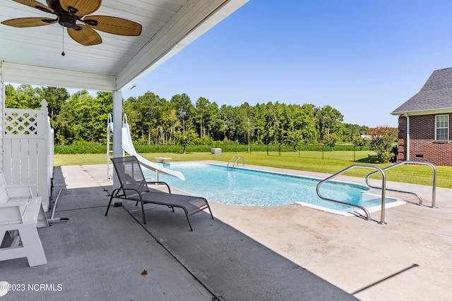 view of swimming pool with a patio area, ceiling fan, a yard, and a water slide