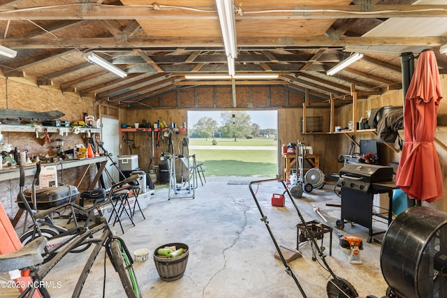 misc room with a workshop area, wooden walls, concrete floors, and vaulted ceiling