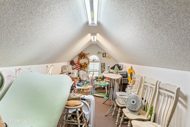 recreation room featuring a textured ceiling, carpet floors, and lofted ceiling