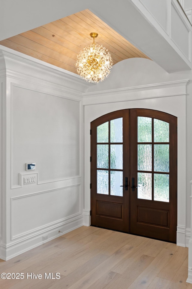 546 Chicamacomico Way, Bald Head Island, NC 28461 - entrance foyer featuring french doors, a chandelier, light wood-style flooring, and arched walkways