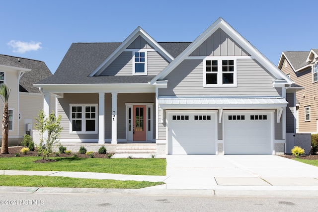 view of front of property featuring a garage, a front lawn, and covered porch