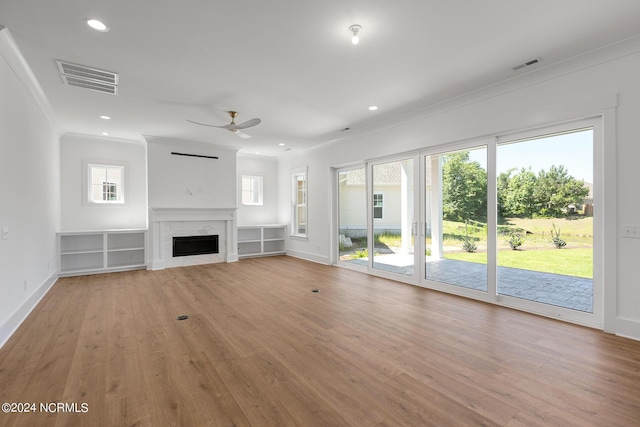 unfurnished living room with crown molding, ceiling fan, a fireplace, and light hardwood / wood-style flooring