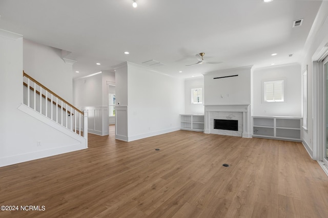 unfurnished living room with ceiling fan, ornamental molding, a fireplace, and light hardwood / wood-style floors