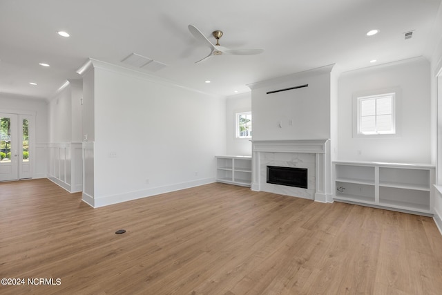 unfurnished living room with a premium fireplace, crown molding, and a healthy amount of sunlight