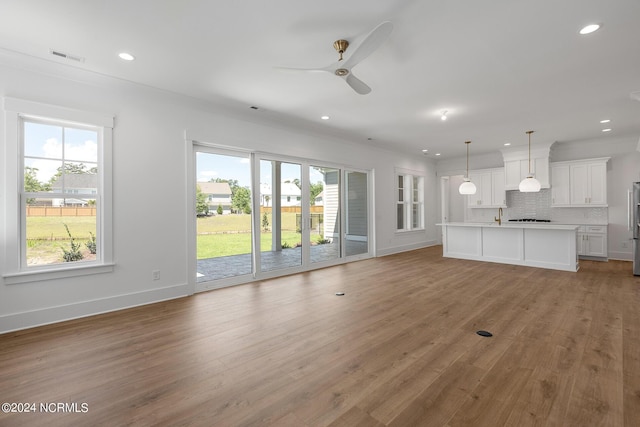 unfurnished living room with crown molding, light hardwood / wood-style flooring, and ceiling fan