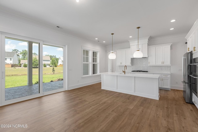 kitchen featuring a kitchen island with sink, backsplash, decorative light fixtures, and white cabinets