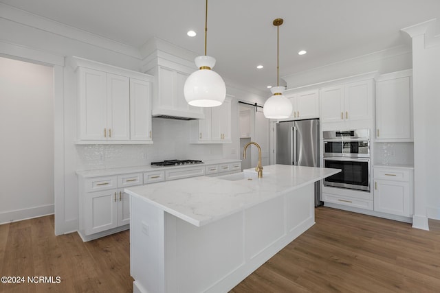 kitchen with sink, white cabinets, a kitchen island with sink, stainless steel appliances, and a barn door