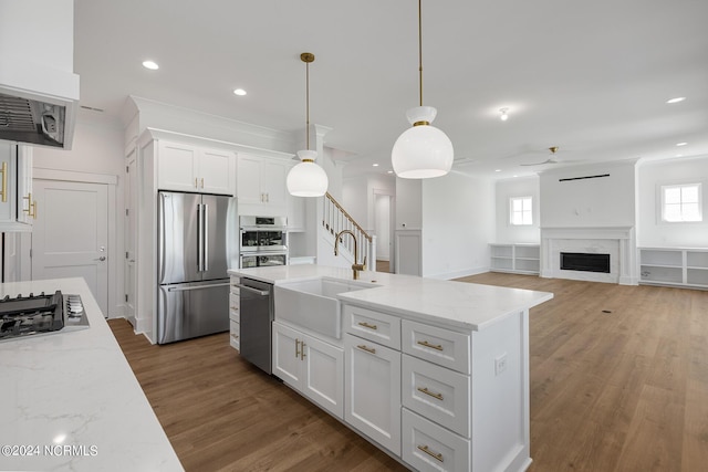 kitchen with sink, appliances with stainless steel finishes, light stone countertops, white cabinets, and decorative light fixtures