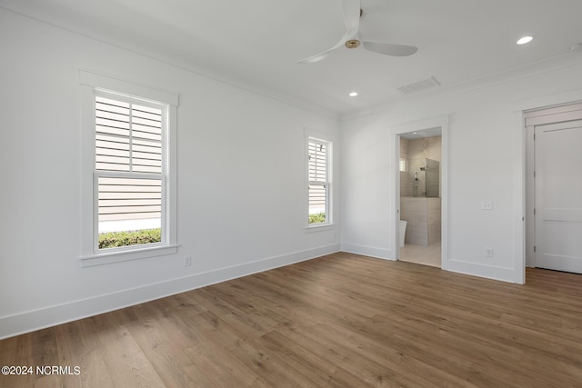 unfurnished bedroom with ceiling fan, ensuite bath, hardwood / wood-style floors, and multiple windows