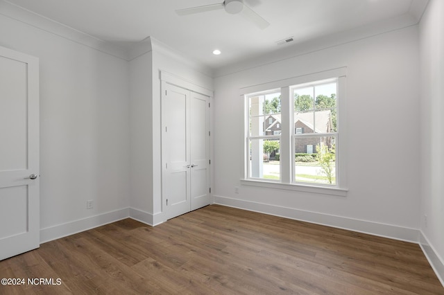 unfurnished bedroom with hardwood / wood-style flooring, ceiling fan, ornamental molding, and a closet