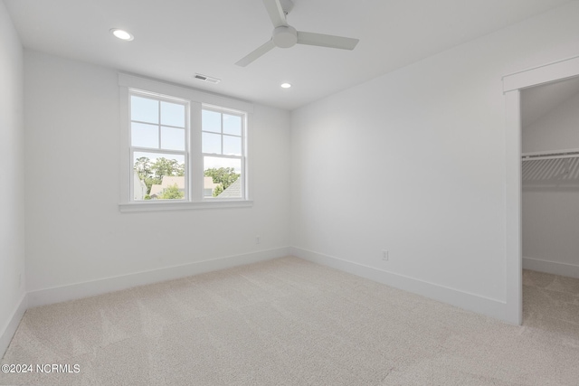 unfurnished bedroom featuring a walk in closet, carpet flooring, ceiling fan, and a closet