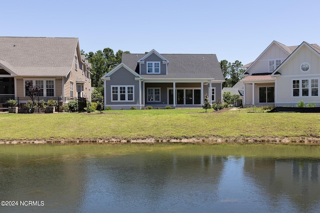 back of property with a water view and a yard