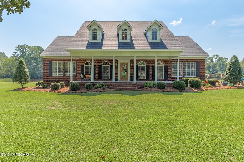 cape cod home with covered porch and a front yard