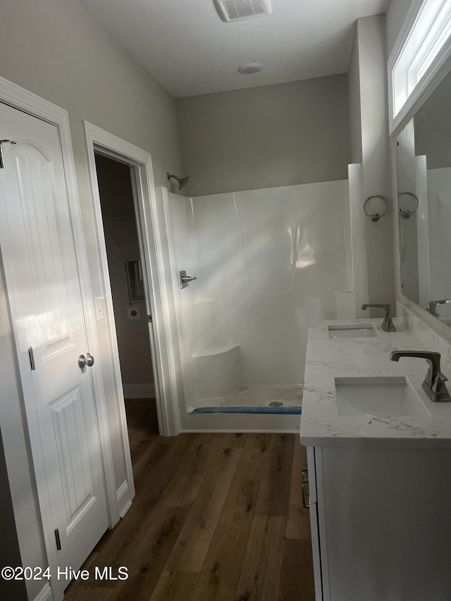 bathroom featuring hardwood / wood-style flooring, vanity, and walk in shower