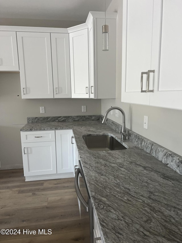 kitchen with stainless steel dishwasher, dark stone counters, sink, dark hardwood / wood-style floors, and white cabinetry