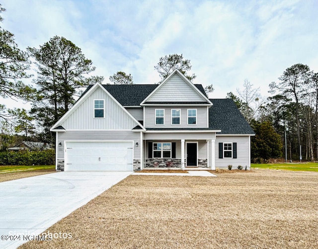 craftsman inspired home with a porch, a front lawn, and a garage