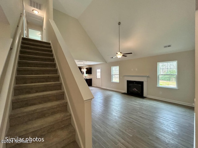 stairway with ceiling fan, dark hardwood / wood-style floors, a healthy amount of sunlight, and high vaulted ceiling