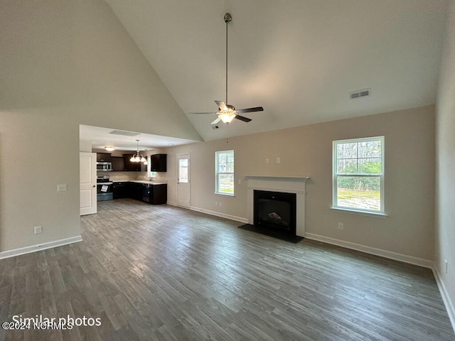 unfurnished living room featuring high vaulted ceiling, ceiling fan with notable chandelier, and dark hardwood / wood-style floors