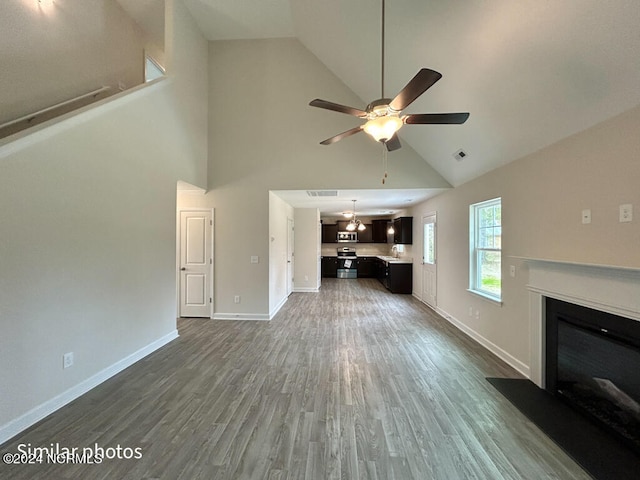 unfurnished living room with high vaulted ceiling, dark hardwood / wood-style floors, and ceiling fan with notable chandelier