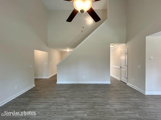 unfurnished room featuring dark hardwood / wood-style floors, ceiling fan, and a towering ceiling