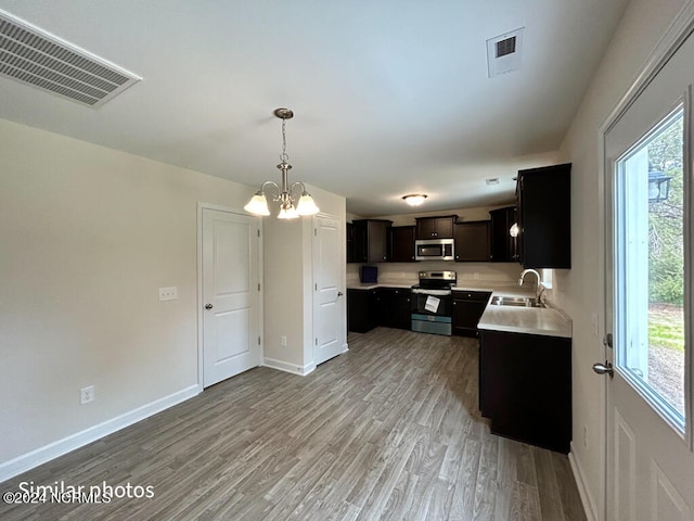 kitchen with plenty of natural light, light hardwood / wood-style floors, appliances with stainless steel finishes, and an inviting chandelier