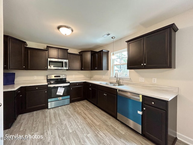 kitchen featuring appliances with stainless steel finishes, light hardwood / wood-style floors, dark brown cabinetry, and sink