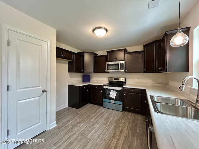 kitchen with pendant lighting, sink, dark brown cabinets, light hardwood / wood-style floors, and stainless steel appliances