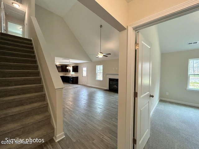 hallway with high vaulted ceiling and hardwood / wood-style flooring