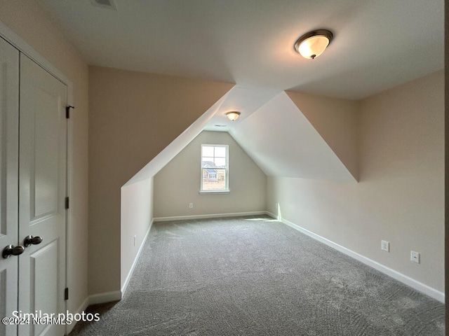 additional living space with dark carpet and vaulted ceiling