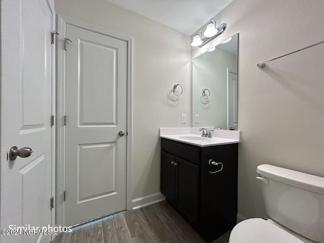 bathroom featuring toilet, vanity, and hardwood / wood-style flooring